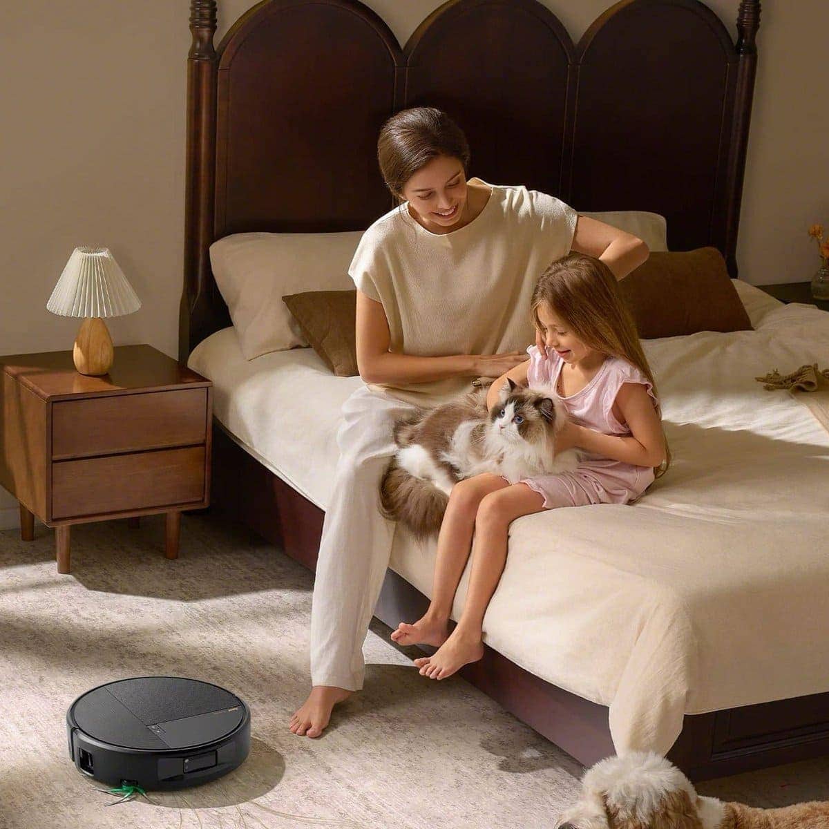 Roomba&reg; Max 875 Combo robot cleaning a bedroom floor beside a parent, a child and a dog on the bed