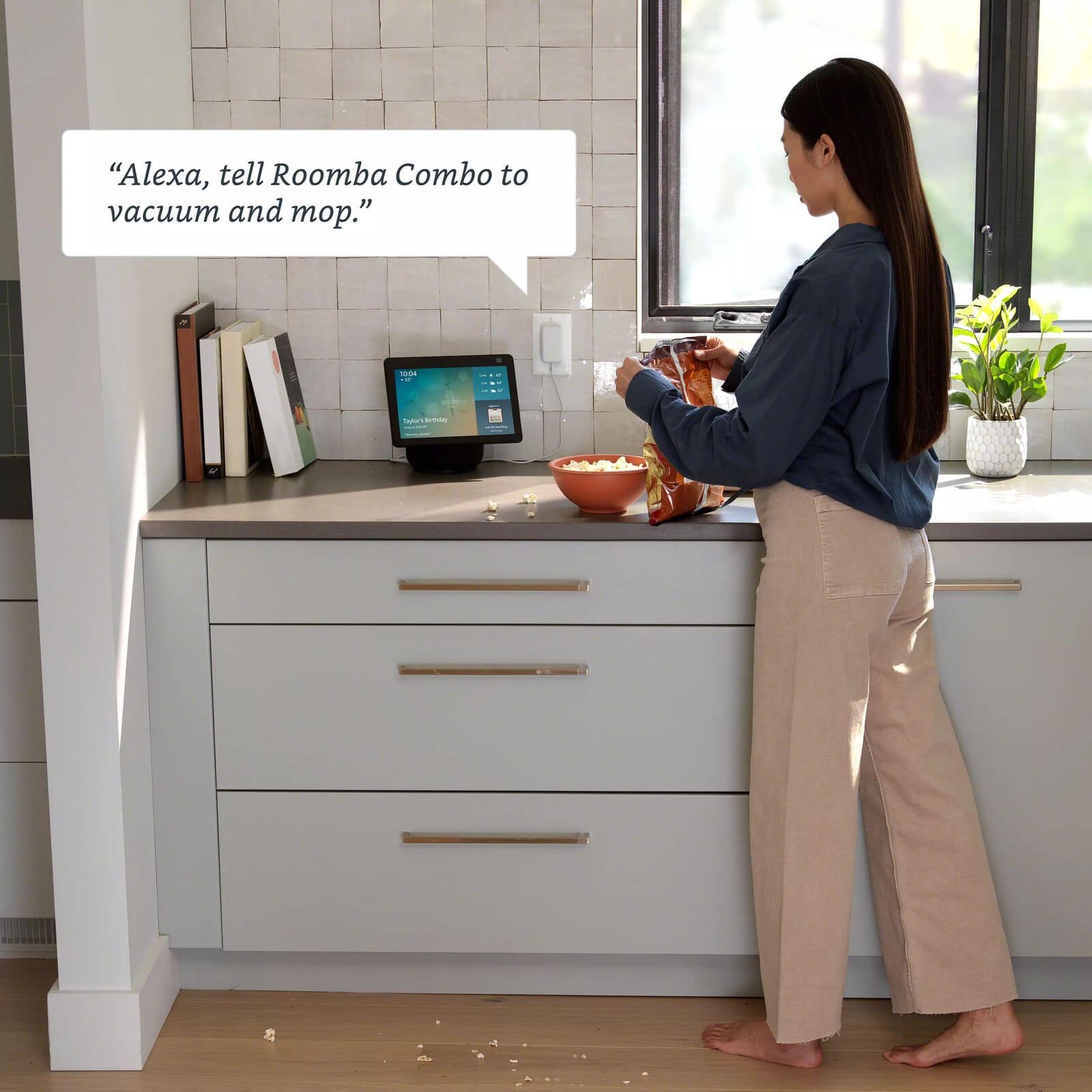 A person starting a Roomba&reg; robot by voice through a smart speaker in the kitchen