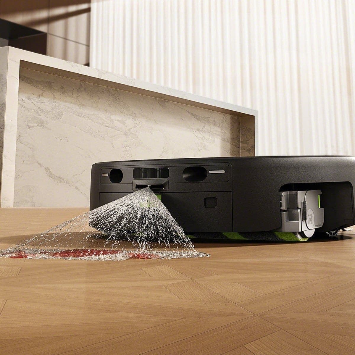 Close-up of the Roomba&reg; Plus 675 Combo robot spraying SprayForce&trade; AI to pre-treat a stain on the floor before mopping